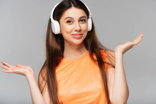 Joyeuse jeune femme dans les écouteurs sans fil écouter de la musique isolée sur gris — Photo de stock