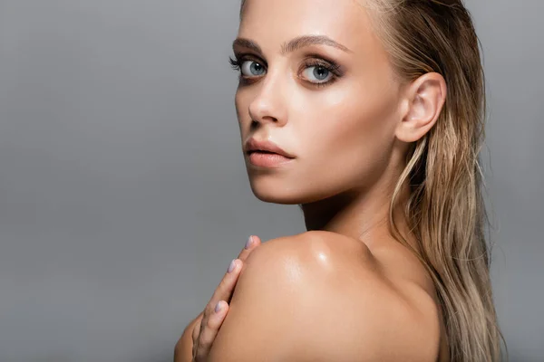 Sensual woman with wet hair touching bare shoulder isolated on grey — Stock Photo