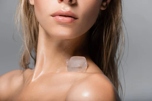 Vista cortada de mulher jovem com cubo de gelo no ombro nu isolado em cinza — Fotografia de Stock