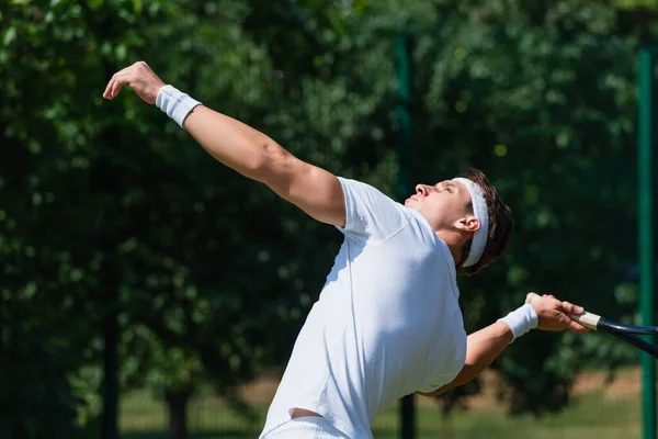 Vista lateral del deportista atlético jugando al tenis al aire libre - foto de stock