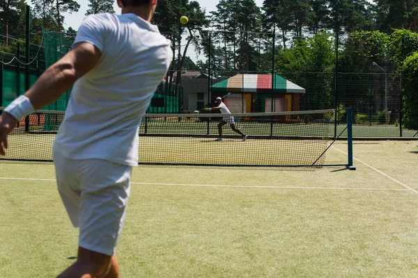 Afro-americano jugando al tenis con un amigo borroso al aire libre - foto de stock