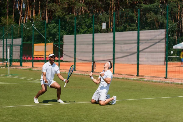 Excited multiethnic tennis players showing yes gesture on court — Stock Photo