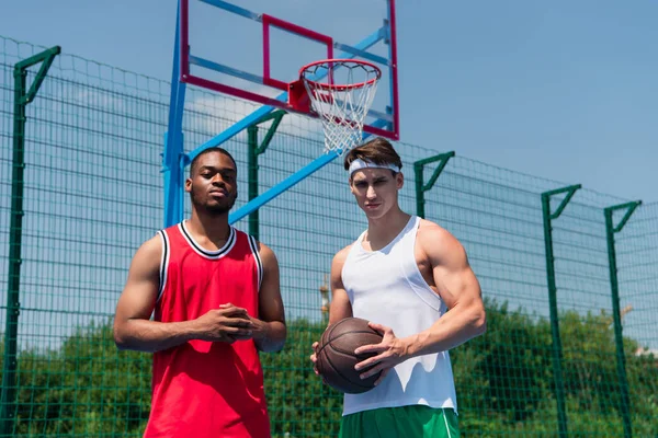 Багатоетнічні баскетболісти тримають м'яч на ігровому майданчику — стокове фото