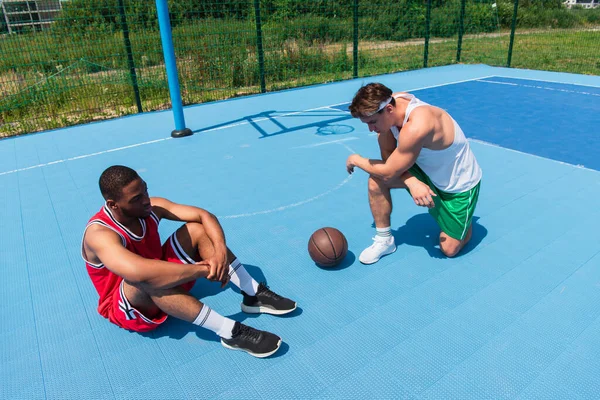 Multiethnische Basketballer ruhen sich auf Spielplatz neben Ball aus — Stock Photo