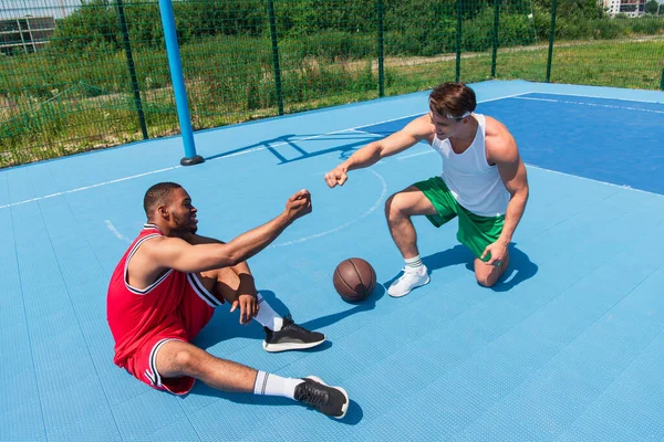 Des joueurs de basket multiethniques souriants font un coup de poing sur une aire de jeux — Photo de stock