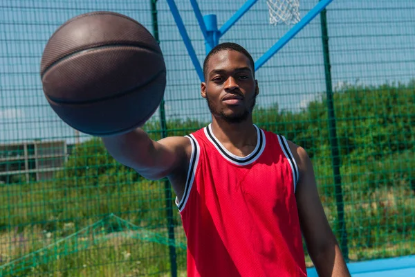 Deportista afroamericano sosteniendo pelota de baloncesto en primer plano borroso - foto de stock