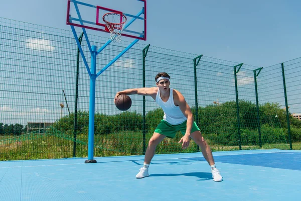 Sportsman playing streetball near hoop on playground — Stock Photo