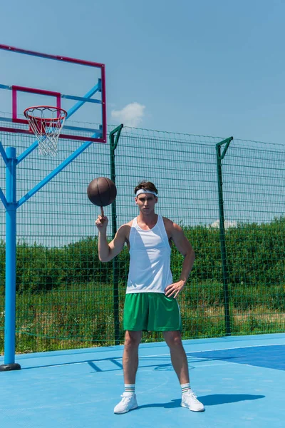 Sportsman holding basketball ball on finger on playground — Stock Photo