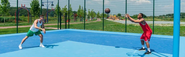 Vista lateral de esportistas inter-raciais jogando streetball, banner — Fotografia de Stock