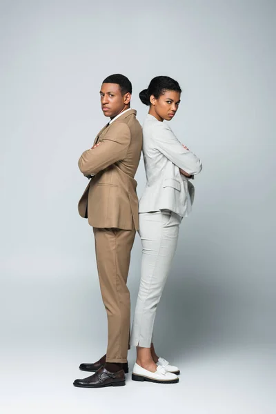Full length of african american business people standing back to back with crossed arms on grey, gender equality concept — Stock Photo
