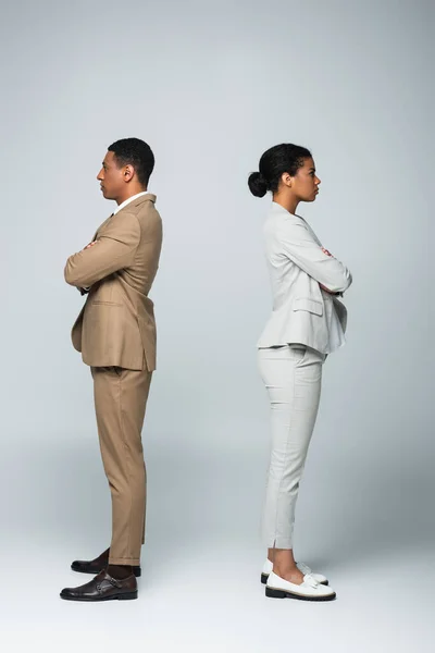 Side view of african american business people standing separately with crossed arms on grey, gender equality concept — Stock Photo