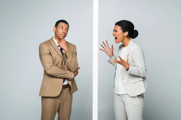 African american businesswoman screaming near wall and pensive businessman on grey — Stock Photo