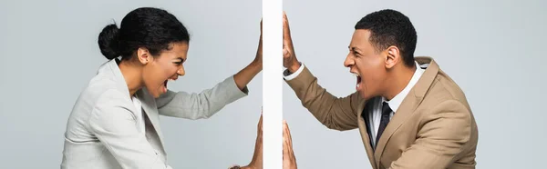 Hombre de negocios afroamericano enojado y mujer de negocios tirando de la pared y gritando en gris, pancarta - foto de stock