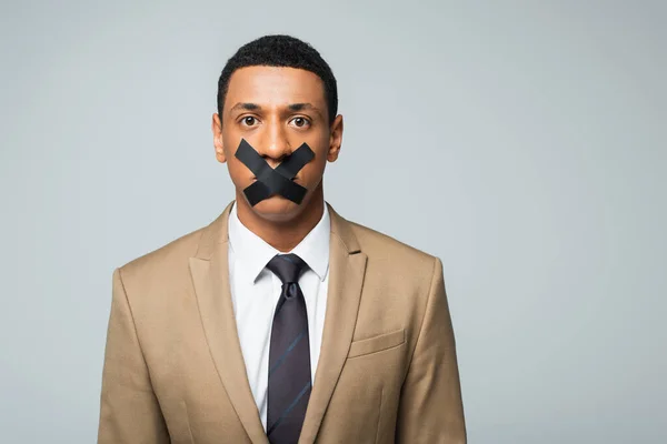 Homme d'affaires afro-américain avec scotch tape sur la bouche isolé sur gris — Photo de stock