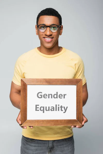 Happy african american man holding placard with gender equality lettering isolated on grey — Stock Photo