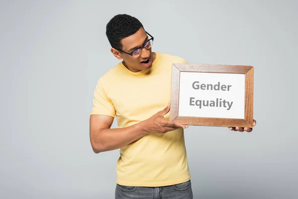 Amazed african american man holding placard with gender equality lettering isolated on grey — Stock Photo