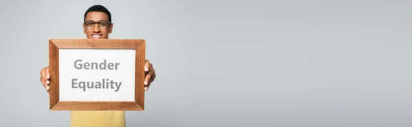 Happy african american man holding placard with gender equality lettering isolated on grey, banner — Stock Photo