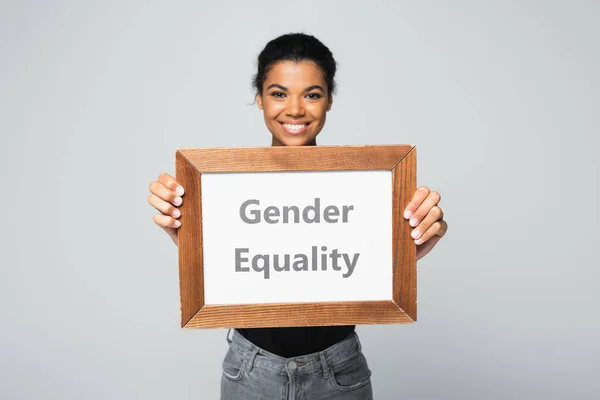 Smiling african american woman holding placard with gender equality lettering isolated on grey — Stock Photo