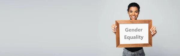 Happy african american woman holding placard with gender equality lettering isolated on grey, banner — Stock Photo