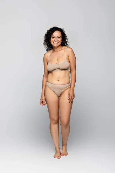 Cheerful african american woman in underwear standing on grey background — Stock Photo