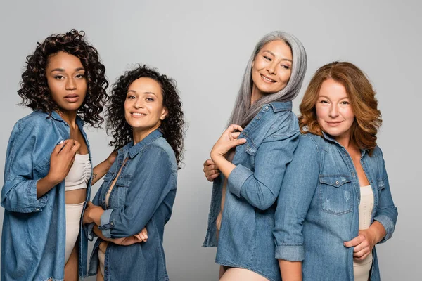 Mujeres multiculturales en lencería y camisas de mezclilla aisladas en gris, concepto positivo para el cuerpo - foto de stock