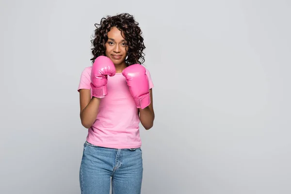 Femme afro-américaine en t-shirt rose et gants de boxe isolés sur gris — Photo de stock