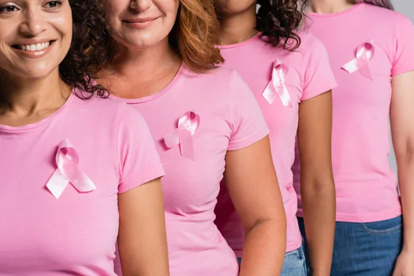 Africano mulher americana com fita rosa na t-shirt sorrindo perto de amigos isolados em cinza — Fotografia de Stock