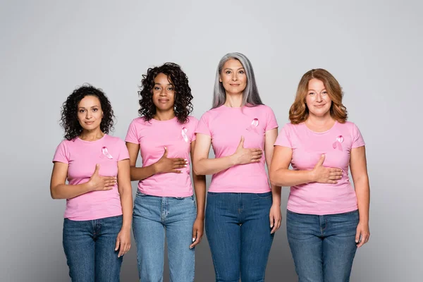 Interrassische Frauen in rosa T-Shirts mit Schleifen auf grauem Hintergrund — Stockfoto