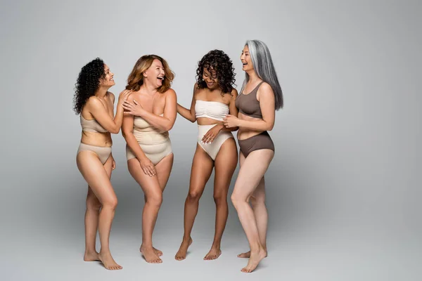 Happy multicultural women in underwear on grey background — Stock Photo