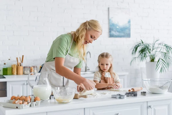 Женщина показывает сырое тесто дочери на кухне — стоковое фото