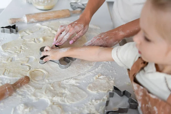 Mutter und verschwommene Tochter schneiden rohen Teig mit Ausstecher — Stockfoto