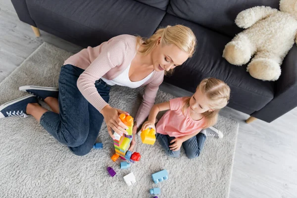 Вид зверху мати і дочка грають з будівельними блоками на підлозі вдома — стокове фото
