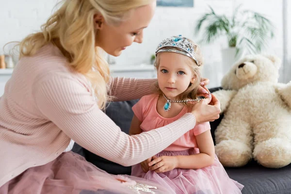 Verschwommene Frau legt Tochter Spielzeugkette an, während sie zu Hause Spaß hat — Stockfoto