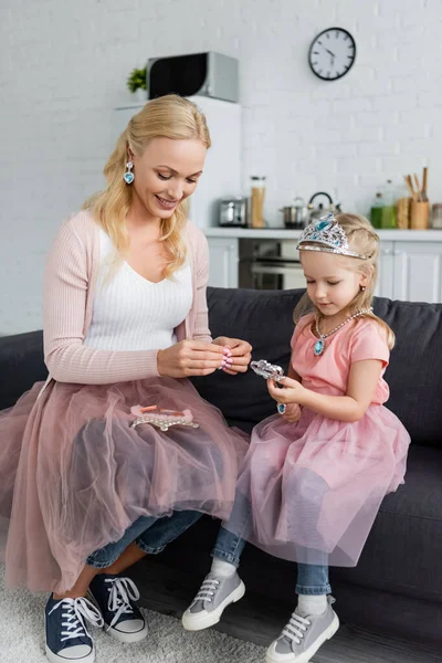 Mère et enfant en costumes de fées jouant sur canapé à la maison — Photo de stock