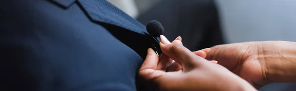 Vue recadrée de l'assistant afro-américain réglage microphone sur costume d'homme d'affaires, bannière — Photo de stock