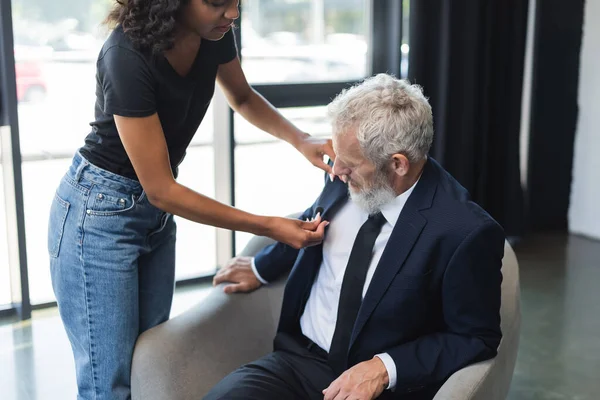 Assistente americano africano encaracolado ajustando microfone em terno de homem de negócios — Fotografia de Stock