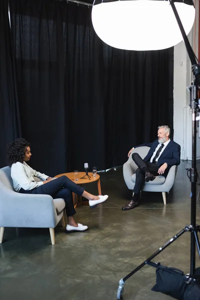 Periodista afroamericano hablando con hombre de negocios durante el talk show - foto de stock