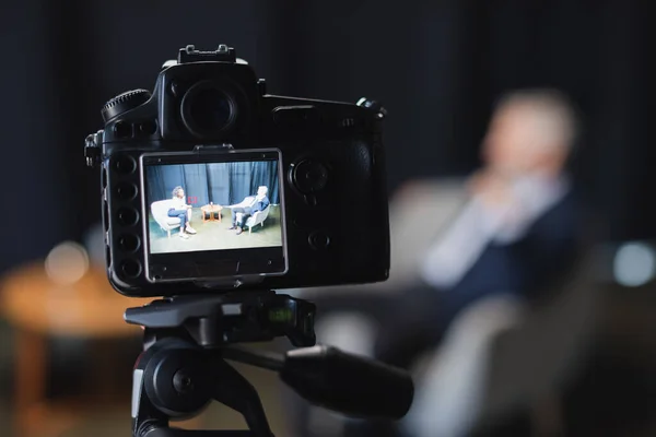 Digital camera with african american journalist talking with businessman in suit during talk show on screen — Stock Photo