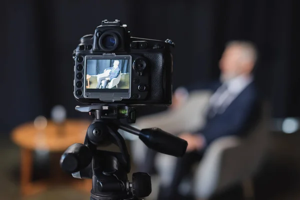 Appareil photo numérique avec homme d'affaires en costume pendant l'interview à l'écran — Photo de stock