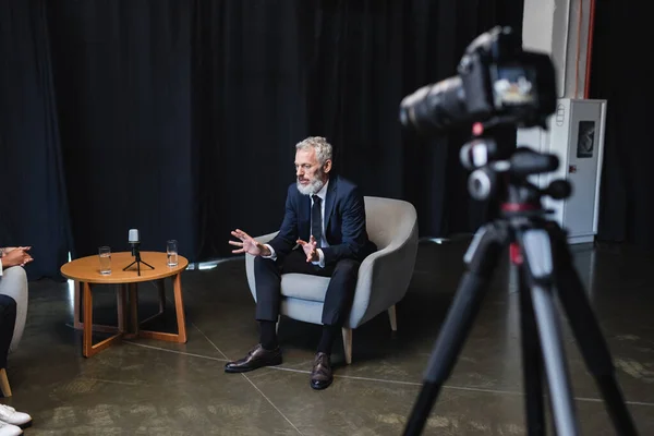 Empresário gesticulando enquanto conversava perto de jornalista afro-americano em estúdio — Fotografia de Stock