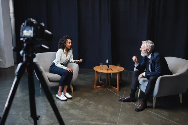 Periodista afroamericano hablando con invitado en estudio de entrevista - foto de stock