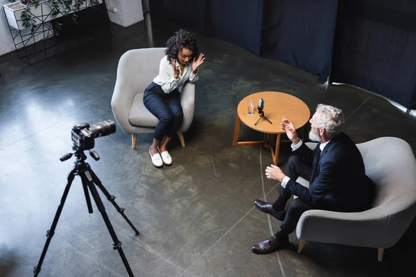 Високий кут зору афроамериканського журналіста, який розмовляє з гостем в інтерв'ю студії — стокове фото