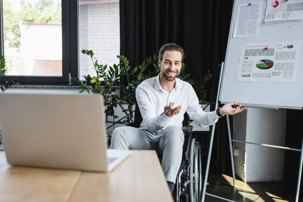 Happy disabled businessman gesturing near flip chart during video call in office — Stock Photo