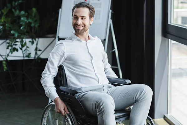Веселий інвалідний бізнесмен дивиться вбік і посміхається в офіс — стокове фото