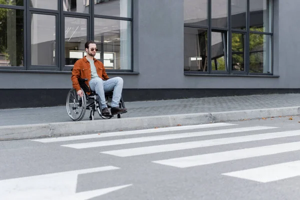 Junger behinderter Mann sitzt im Rollstuhl nahe Grenze und Fußgängerüberweg — Stockfoto