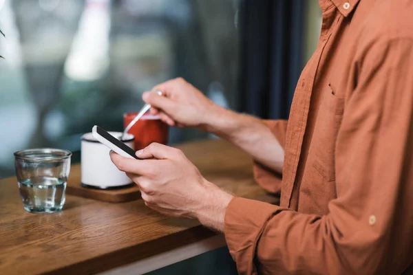 Vista ritagliata di uomo sms su smartphone in caffè — Foto stock