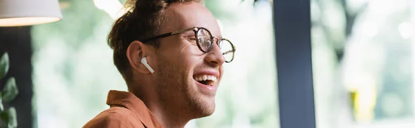 Hombre feliz en gafas y auriculares riendo en la cafetería, pancarta - foto de stock