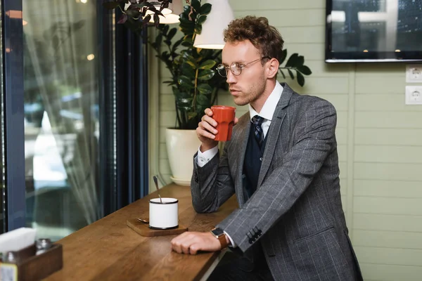 Homem de negócios confiante em terno segurando xícara de café no café — Fotografia de Stock