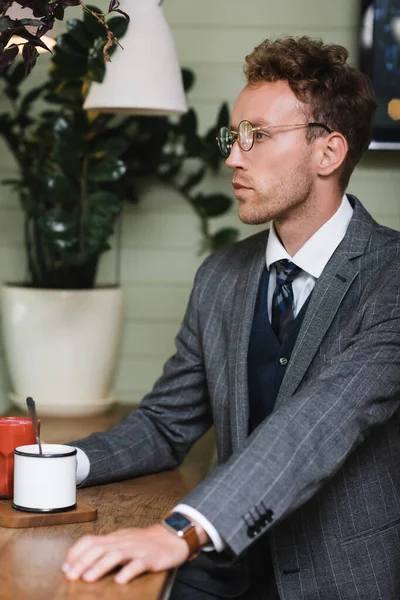 Joven hombre de negocios en ropa formal sentado en la cafetería - foto de stock