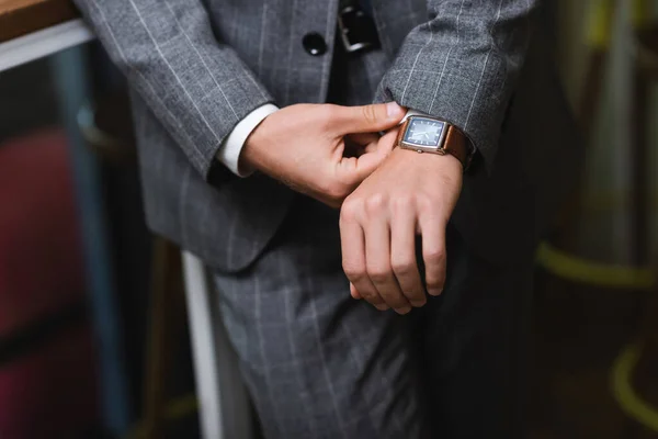 Vista ritagliata di giovane uomo d'affari in abbigliamento formale orologio da polso di regolazione — Foto stock